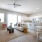 Spacious and well lit living room with wood flooring, large windows and open access to the kitchen