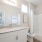Large well lit bathroom with white accents 